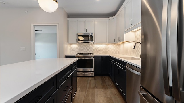 kitchen featuring tasteful backsplash, light countertops, appliances with stainless steel finishes, white cabinetry, and a sink