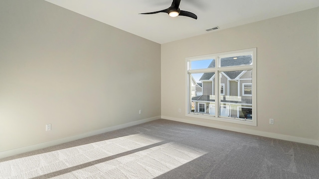 carpeted empty room featuring visible vents, a ceiling fan, and baseboards