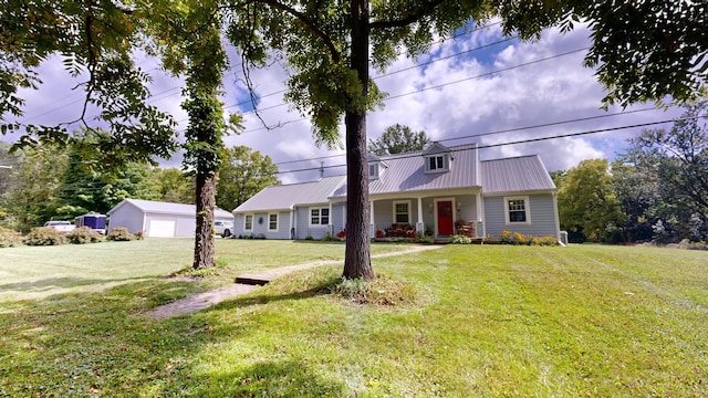 view of front facade featuring a front yard, metal roof, a detached garage, and an outdoor structure