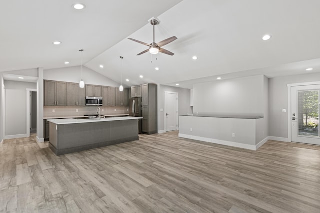 kitchen with sink, light hardwood / wood-style floors, decorative backsplash, decorative light fixtures, and vaulted ceiling