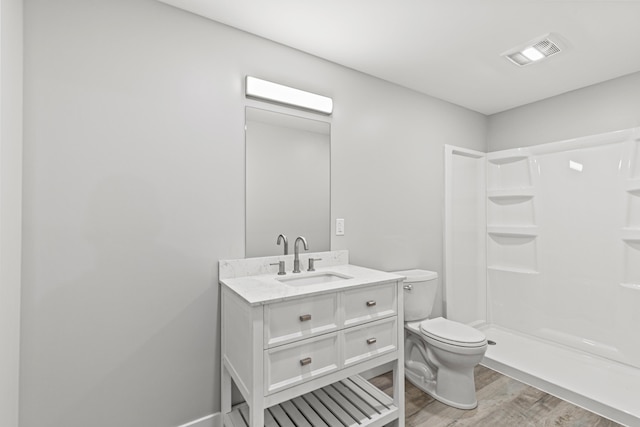 bathroom with vanity, hardwood / wood-style floors, walk in shower, and toilet