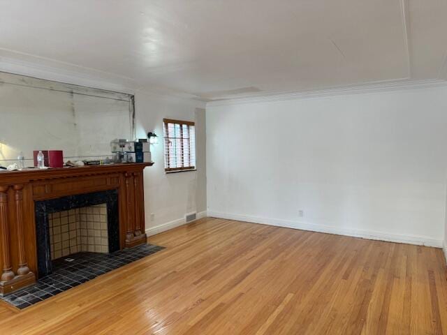 unfurnished living room featuring ornamental molding, a tiled fireplace, and hardwood / wood-style floors