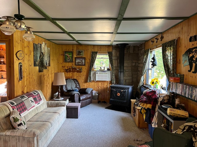 living room with carpet, wooden walls, and a wood stove