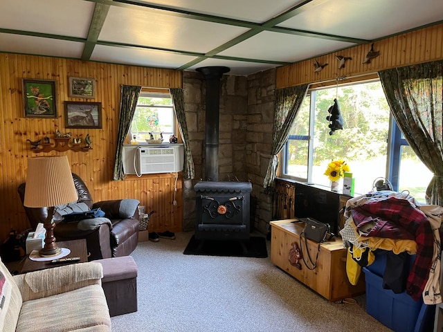 carpeted living room with wood walls, a wood stove, coffered ceiling, and cooling unit