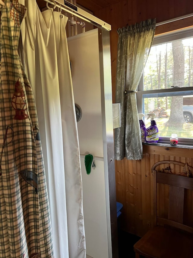 bathroom featuring wood walls and a shower with shower curtain