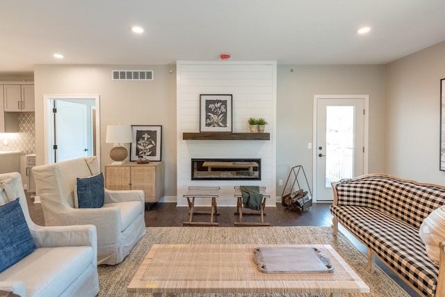 living area with recessed lighting, visible vents, a large fireplace, and wood finished floors