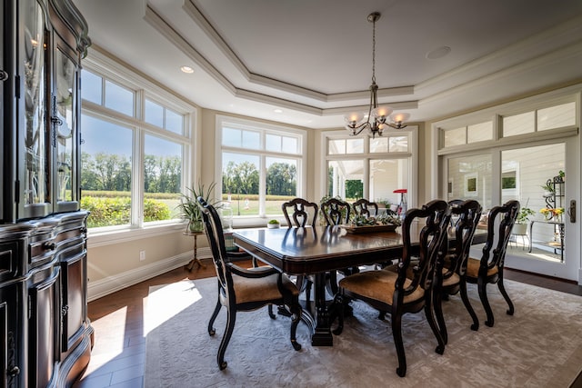 dining area with dark hardwood / wood-style flooring, ornamental molding, a tray ceiling, and a notable chandelier