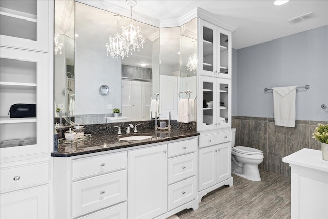 bathroom featuring toilet, a shower with door, tile walls, a chandelier, and vanity