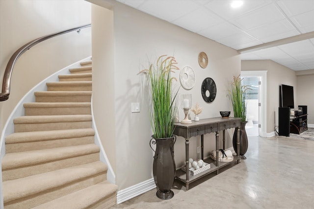 stairs featuring a drop ceiling and concrete flooring