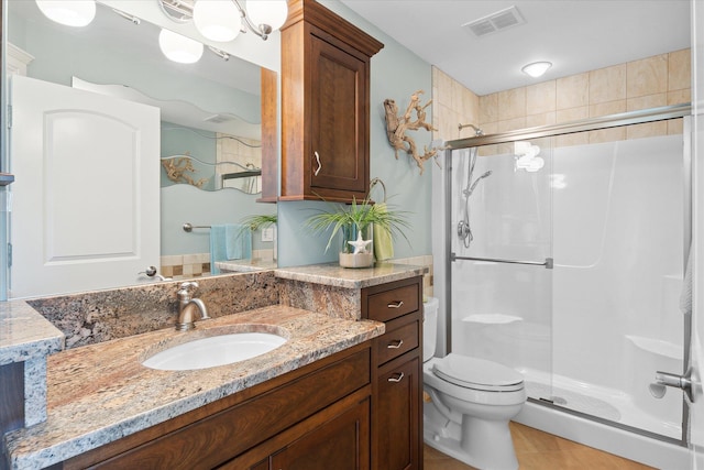 bathroom featuring an enclosed shower, vanity, tile patterned floors, and toilet