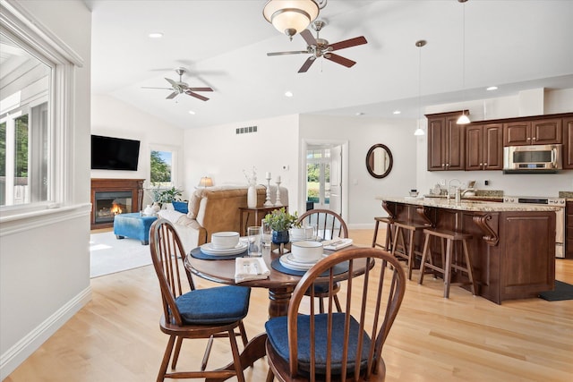 dining room with ceiling fan, lofted ceiling, and light wood-type flooring