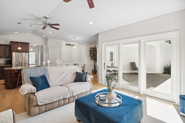 living room featuring ceiling fan with notable chandelier, lofted ceiling, and light hardwood / wood-style floors