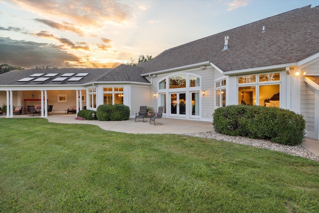 back house at dusk with a yard, french doors, and a patio