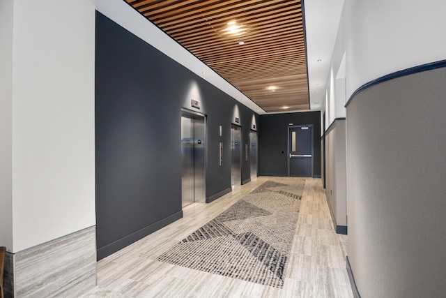 hallway featuring elevator, light hardwood / wood-style flooring, and wood ceiling