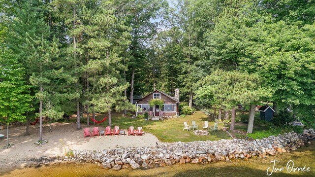 rear view of property featuring a water view, an outbuilding, and a lawn