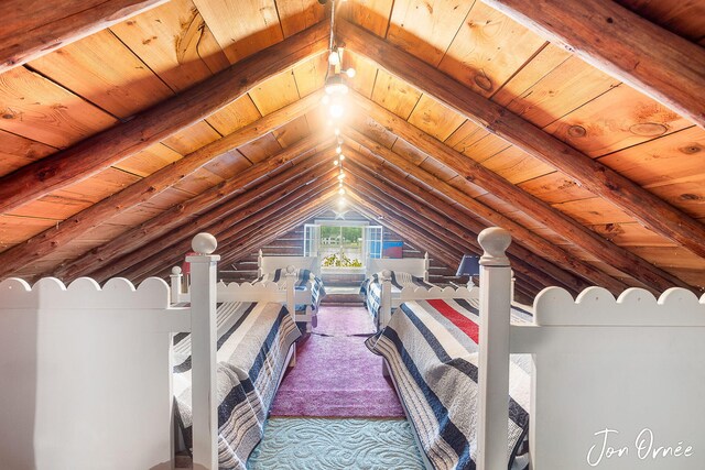 unfurnished bedroom with lofted ceiling with beams, carpet, and wooden ceiling