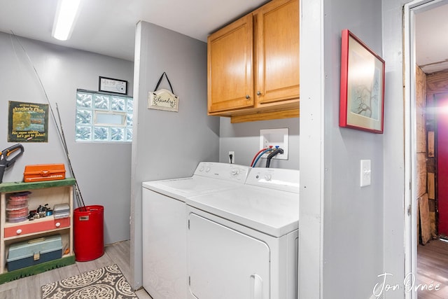 washroom with cabinets, washing machine and dryer, and light hardwood / wood-style flooring