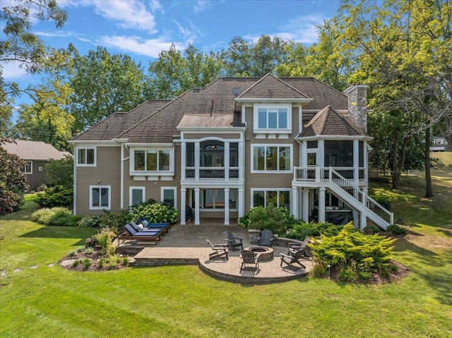 back of property with a fire pit, a sunroom, a yard, and a patio area