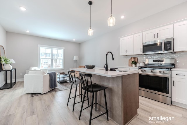 kitchen featuring stainless steel appliances, white cabinetry, sink, and a kitchen island with sink