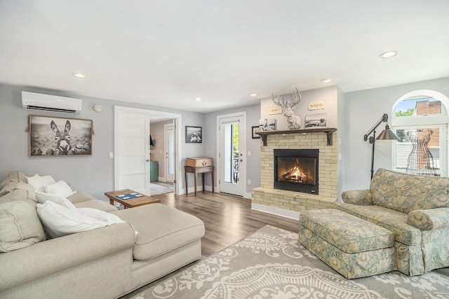 living room featuring light wood-type flooring, a wall mounted air conditioner, and a brick fireplace