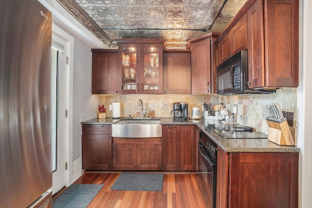 bar with wood finished floors, an ornate ceiling, a sink, decorative backsplash, and black appliances