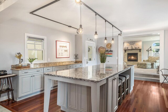 kitchen featuring a brick fireplace, dark hardwood / wood-style flooring, gray cabinetry, and light stone countertops