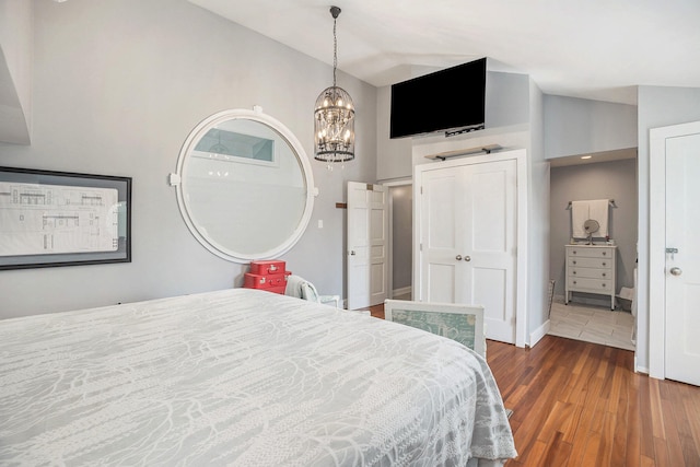 bedroom featuring high vaulted ceiling, an inviting chandelier, and hardwood / wood-style flooring