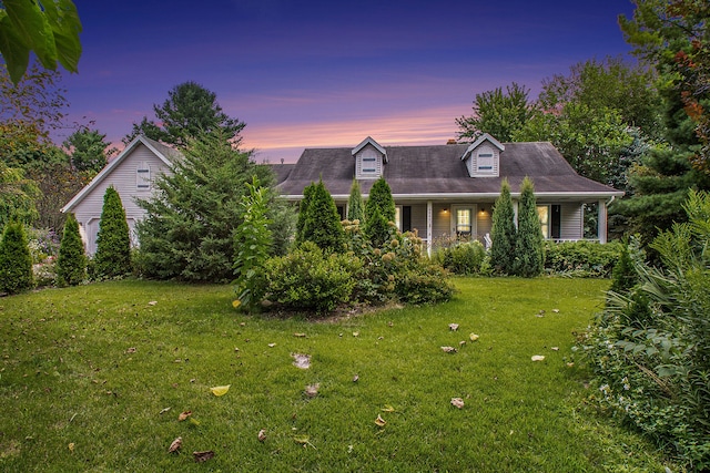 cape cod house featuring a yard