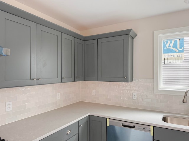 kitchen featuring gray cabinetry, sink, backsplash, and stainless steel dishwasher