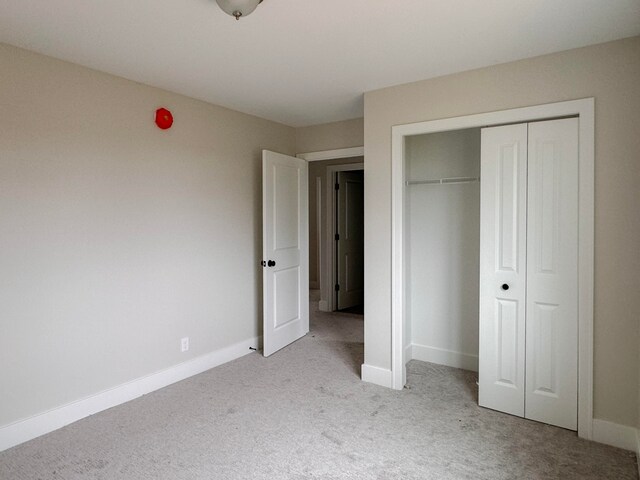 unfurnished bedroom featuring light carpet and a closet