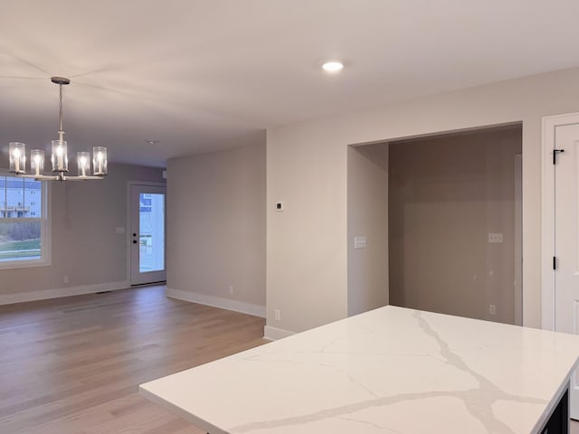 kitchen featuring pendant lighting, light hardwood / wood-style flooring, and an inviting chandelier