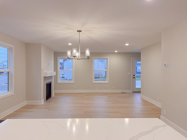 unfurnished living room with a chandelier and light hardwood / wood-style floors