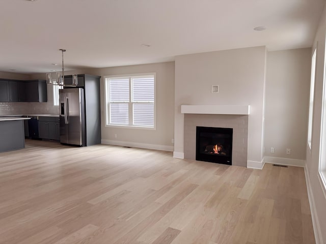 unfurnished living room featuring light hardwood / wood-style flooring and a chandelier