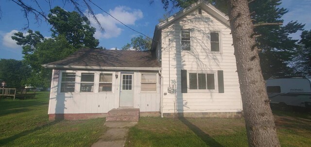 traditional-style house with entry steps, a front lawn, and roof with shingles