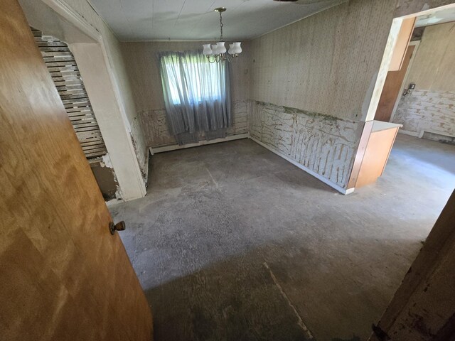 unfurnished dining area featuring a baseboard heating unit, an inviting chandelier, and concrete floors