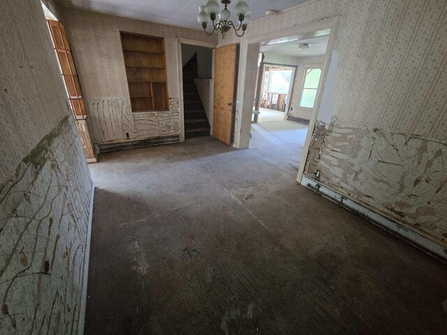 empty room featuring a notable chandelier and built in shelves