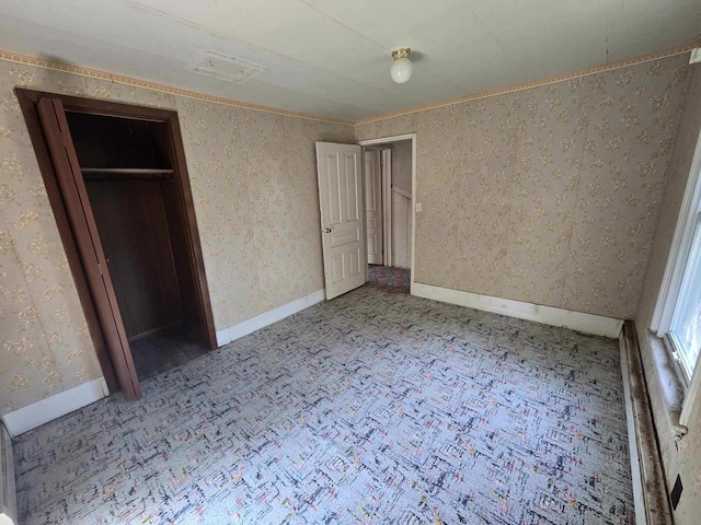 unfurnished bedroom with carpet, a closet, baseboards, and wallpapered walls