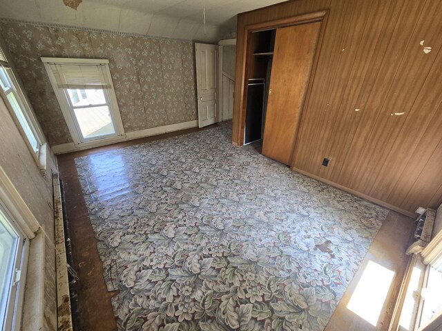 unfurnished bedroom with a closet and wooden walls