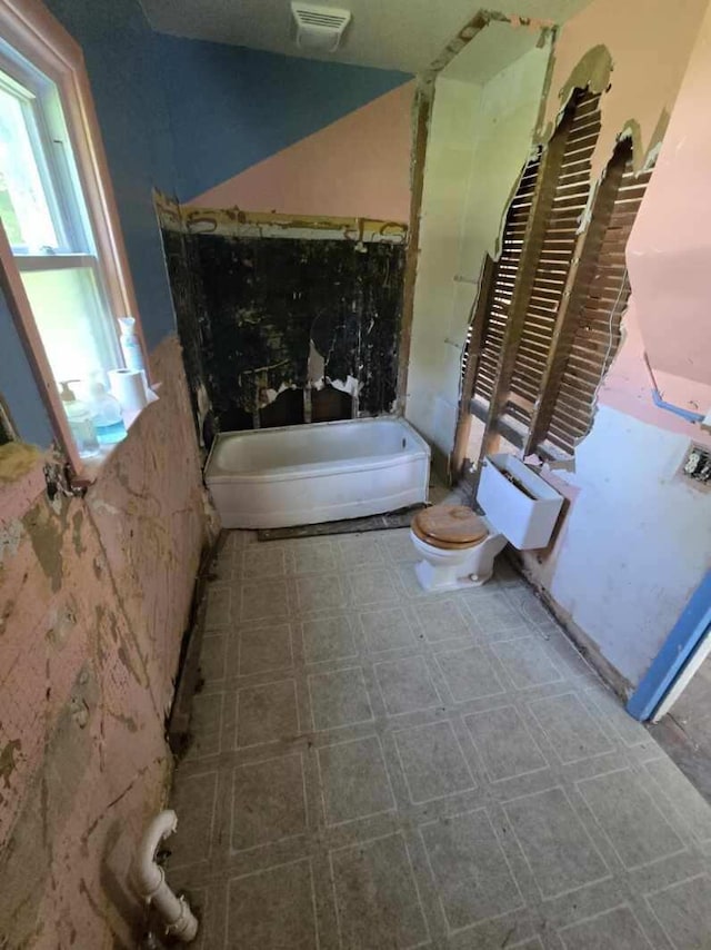 bathroom featuring tile patterned floors, visible vents, toilet, and a bathing tub