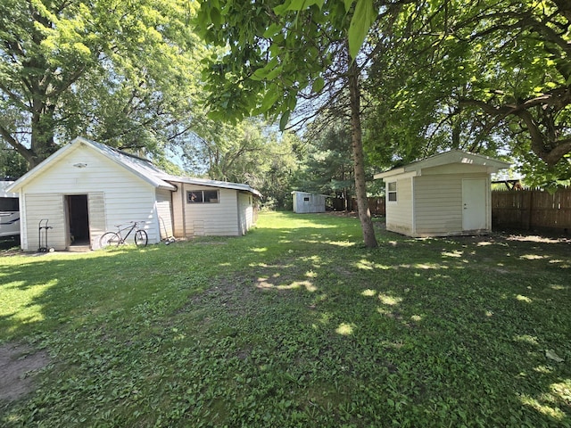 view of yard featuring an outbuilding, a shed, and fence