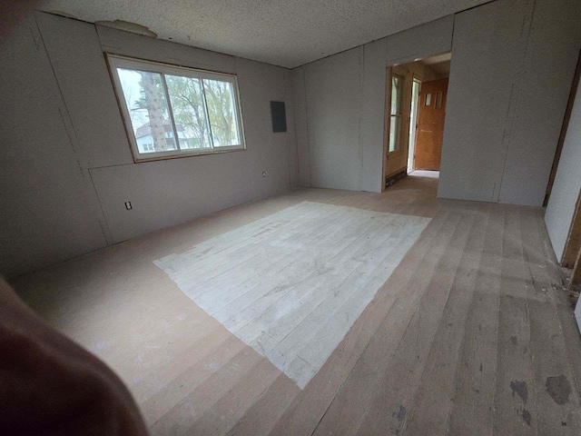 spare room with a textured ceiling and light hardwood / wood-style flooring