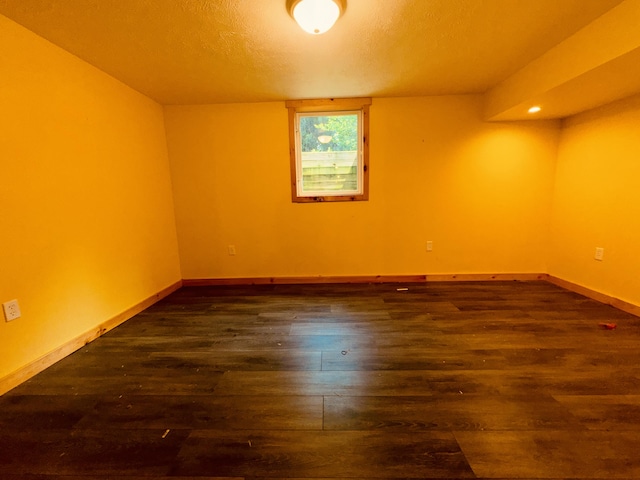 spare room with a textured ceiling and dark hardwood / wood-style flooring