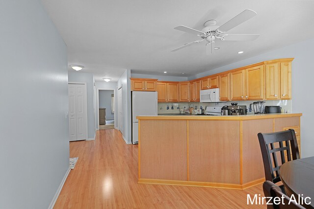 kitchen featuring light brown cabinets, ceiling fan, kitchen peninsula, light wood-type flooring, and white appliances