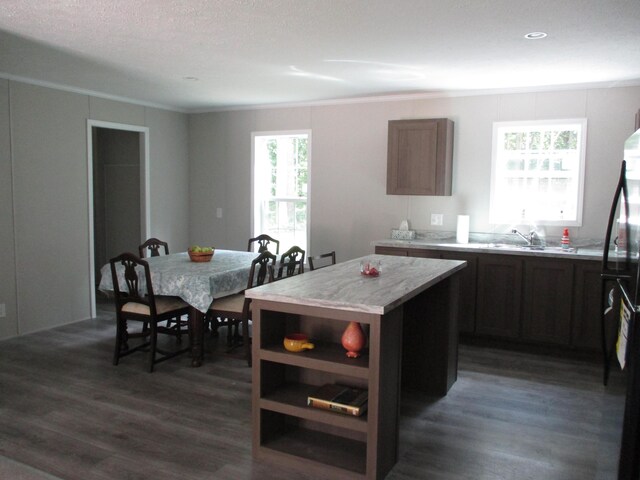 kitchen featuring a kitchen island, dark wood-type flooring, sink, black refrigerator, and a textured ceiling