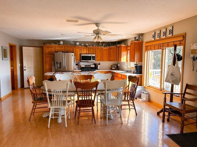 dining space with ceiling fan, light hardwood / wood-style floors, and sink