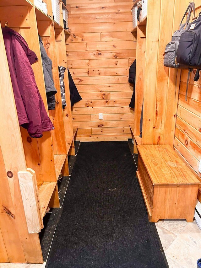 mudroom with tile patterned floors and wood walls