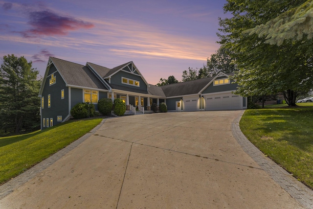 view of front of home with covered porch, driveway, an attached garage, and a front lawn