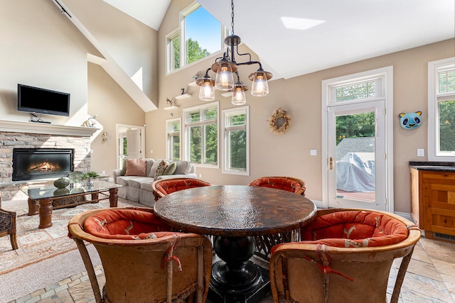 dining room with a fireplace, a notable chandelier, a high ceiling, and light tile patterned floors