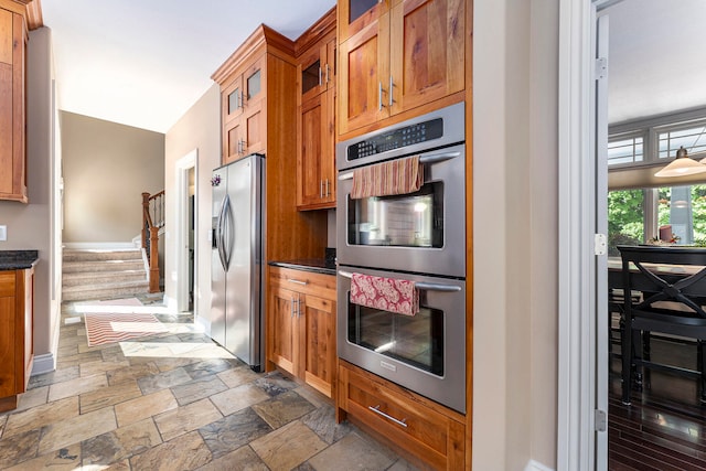 kitchen with dark tile patterned flooring, stainless steel appliances, and dark stone countertops