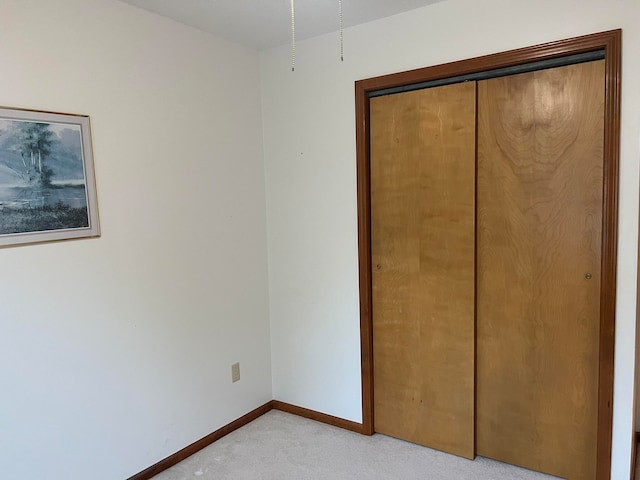 unfurnished bedroom with light colored carpet and a closet